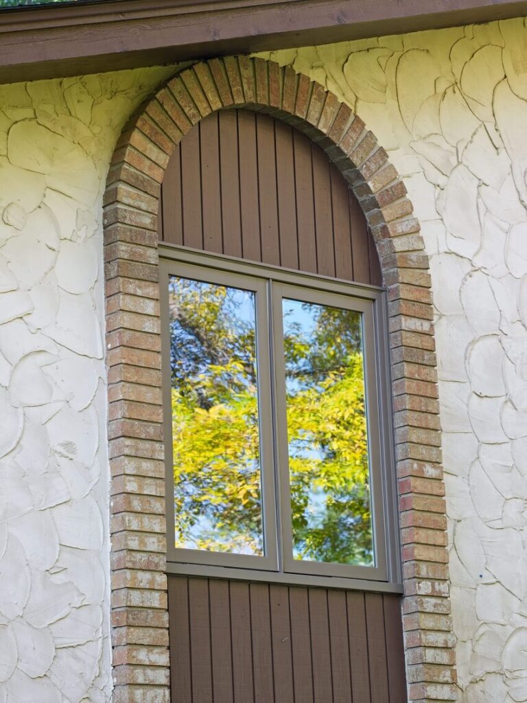 home with brick arched around the window with wood paneling